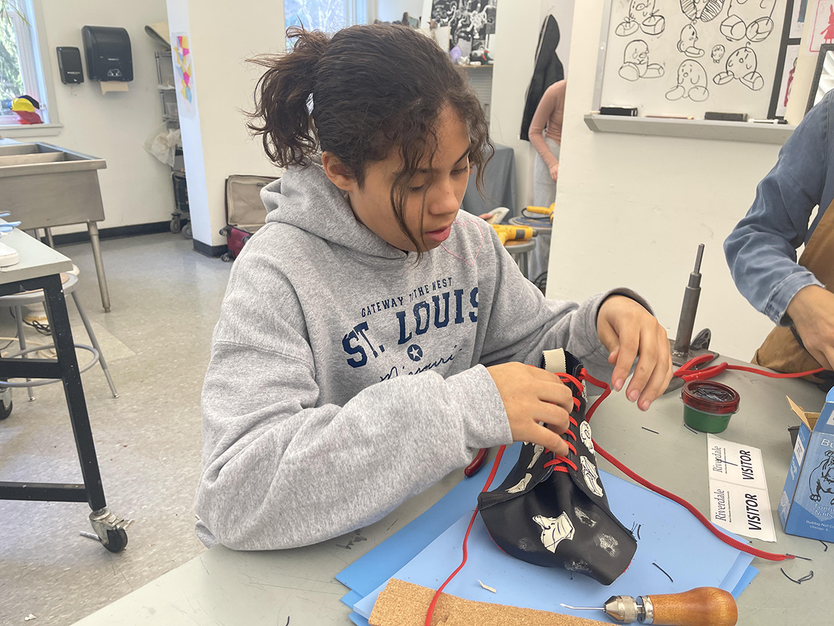 A student sits at a table and builds a custom shoe.