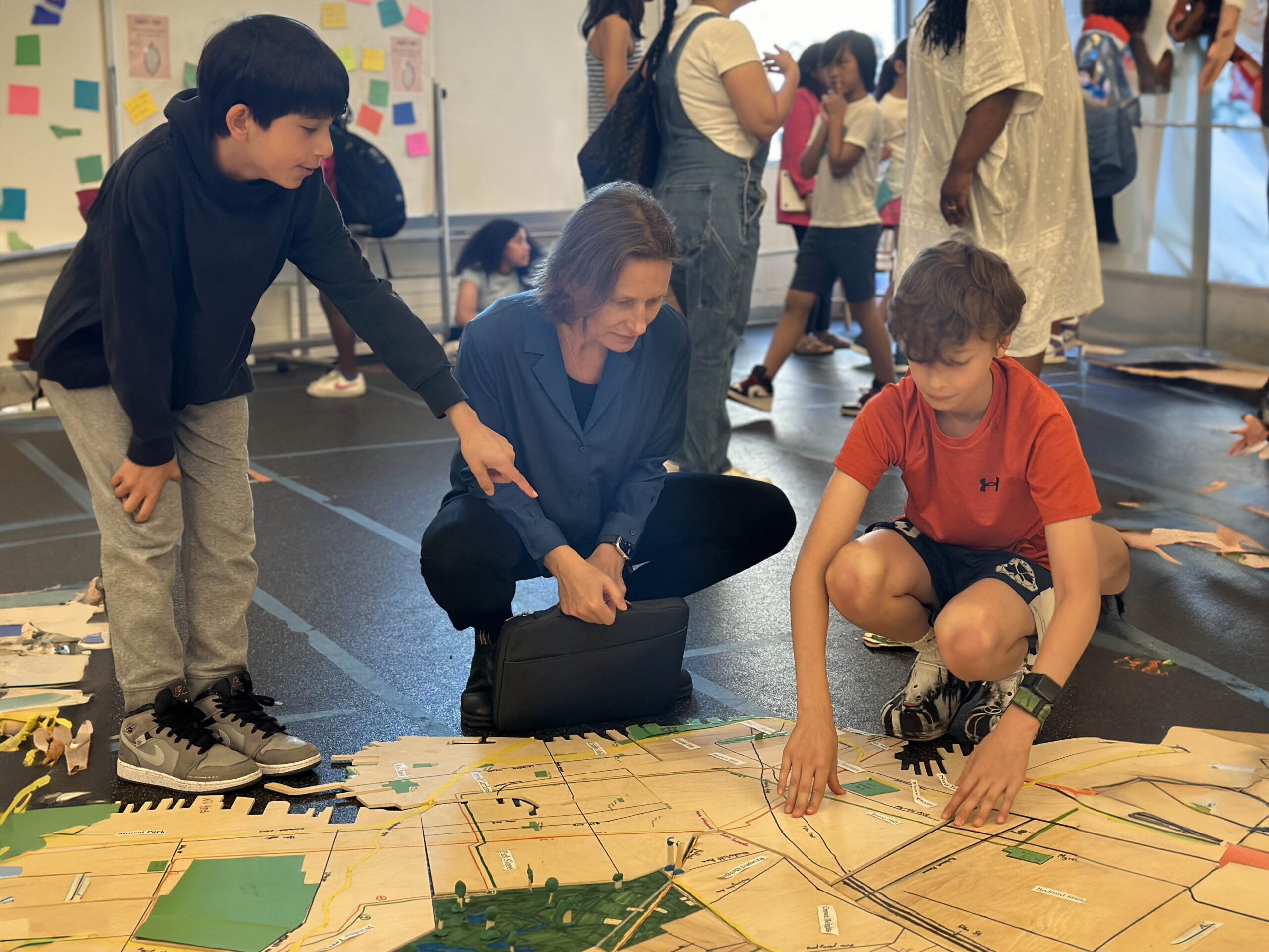 Students and an adult look at a map on the floor